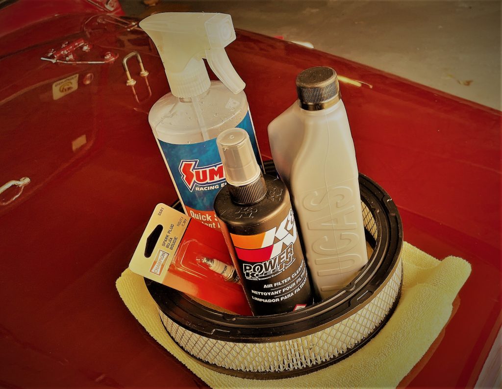 Car care maintenance supplies stacked on the hood of an old car