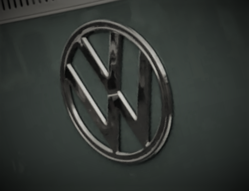 Stylized close-up photo of a VW emblem on the front of a 1960s-era type 2 transporter bus