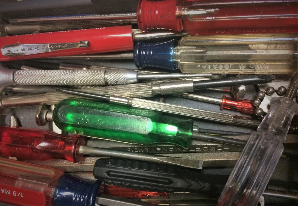 cluster of small precision scredwrivers grouped together in a drawer