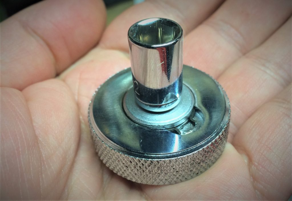 man holding a thumbwheel ratchet in the palm of his hand