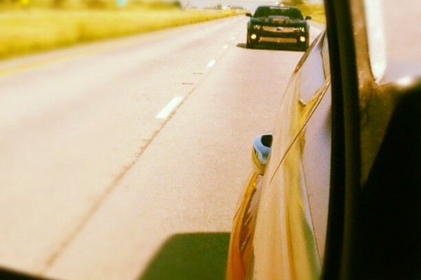 chevy camaro in the side mirror of a car on the highway