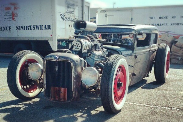 rat rod with supercharged v8 in parking lot