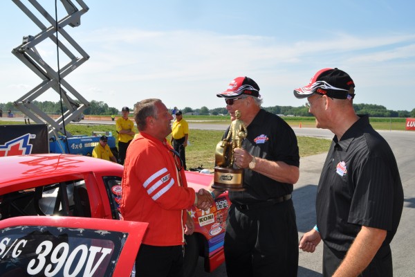racer being handed a nhra wally trophy