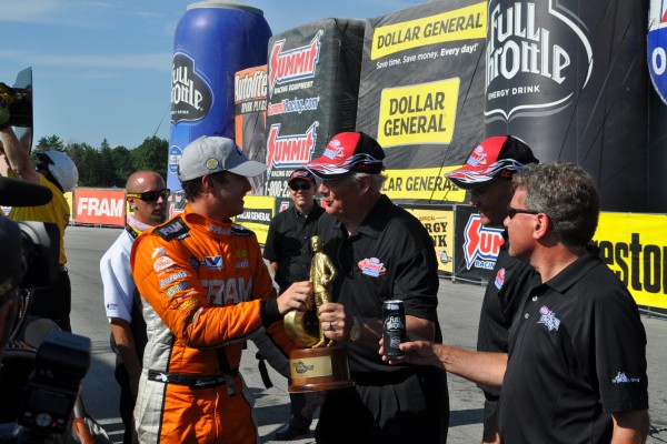 drag racer being handed a nhra wally trophy