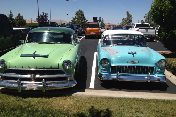 a 1955 chevy and vintage hudson in a parking lot