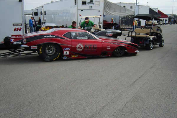 chevy camaro drag race car near semis in pits