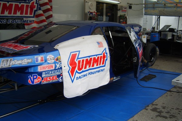 nhra pro stock camaro in pits near semi trailer