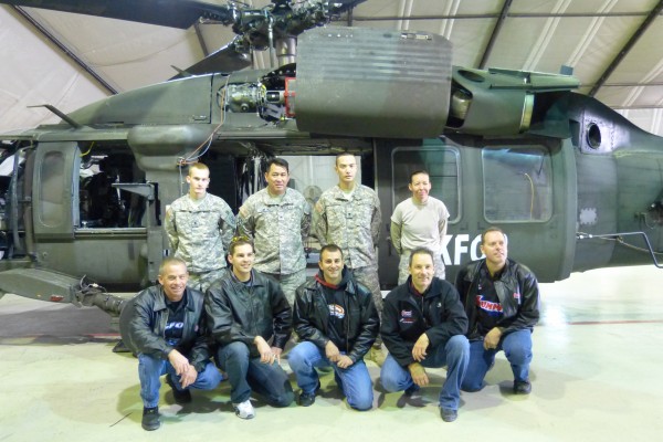 nhra drivers posing for photo with troops and blackhawk helicopter