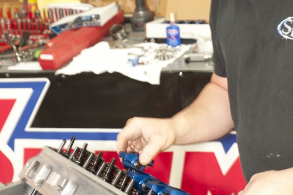 man installing rocker arms into a cylinder head