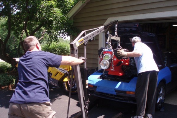 men dropping v8 engine into a mazda RX-7