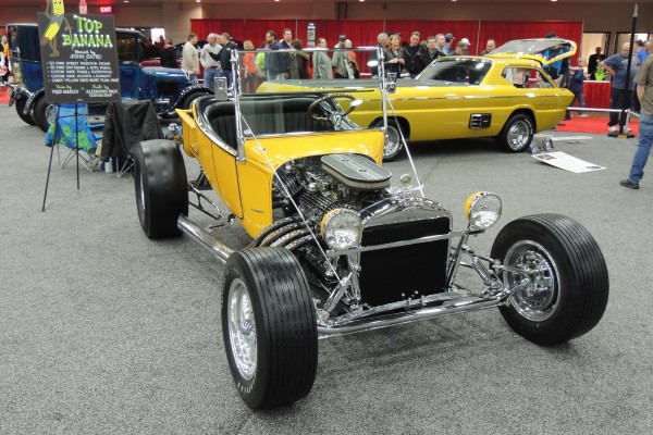 yellow ford t bucket hot rod at a car show