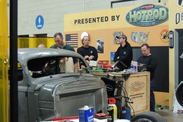 men at hot rod display at car show