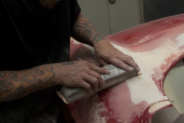 man sanding bodywork on a car