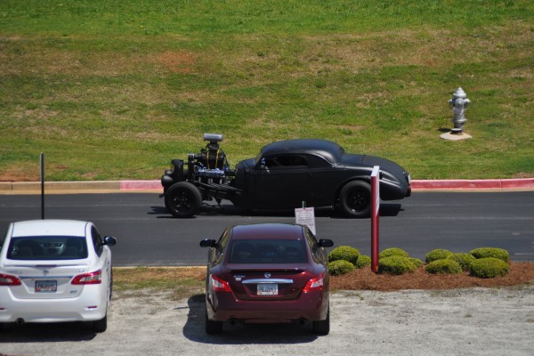 stretched hot rod with supercharged v8 driving into car show