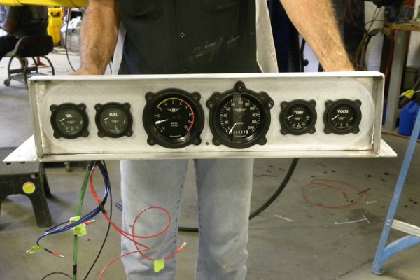man holding custom gauge panel for a hot rod