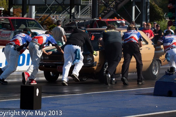 men pushing a drag car back to staging area after burnout