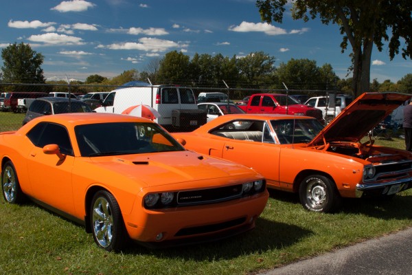 a pair of old and new mopars at a car show