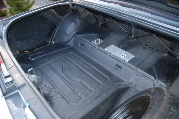 filter and pump doubler plates on floor of a classic car trunk