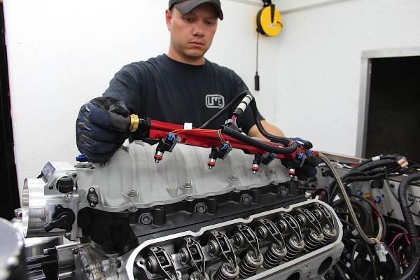 man installing fuel rails onto a gm ls v8 engine