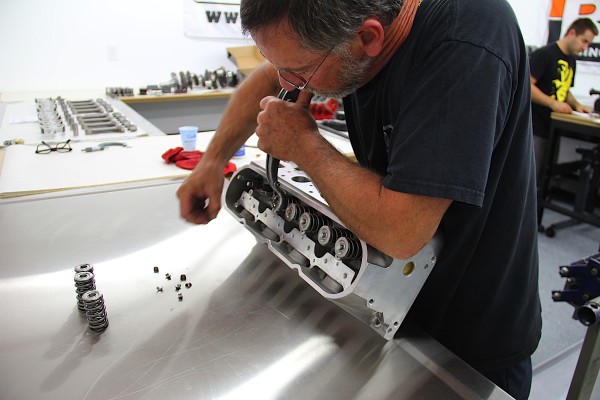 man fitting comp cams valve springs onto a cylinder head
