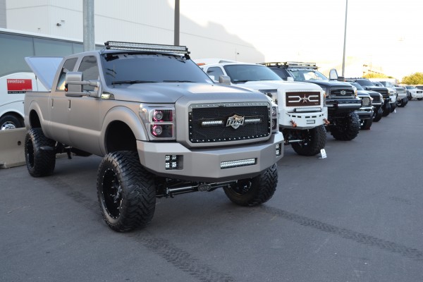 row of custom lifted trucks displayed outside at SEMA 2013