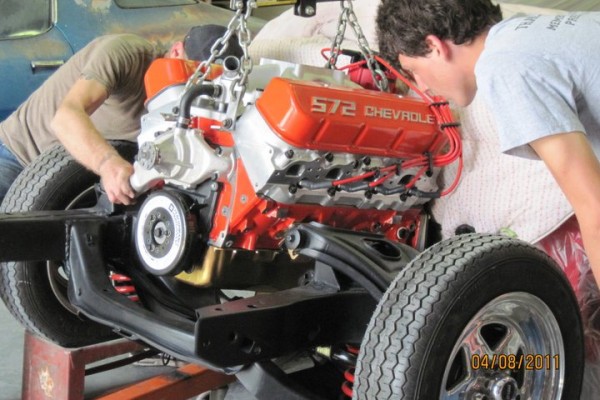 men installing big block engine onto a 1967 camaro subframe