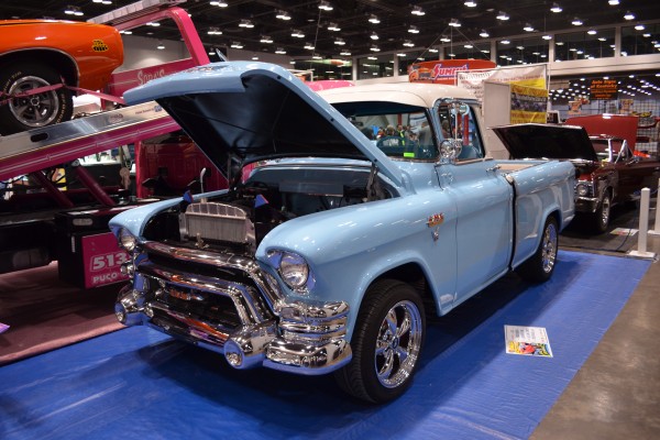 vintage GMC pickup truck with custom wheels displayed at indoor car show