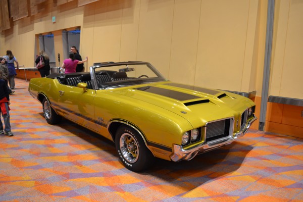 gold Olds Custlass 442 convertible displayed at indoor car show