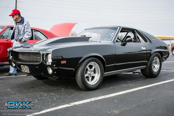a black amc amx muscle car with a cowl hood and custom wheels