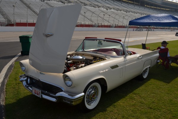 a vintage ford thunderbird coupe with its hood up at a car show