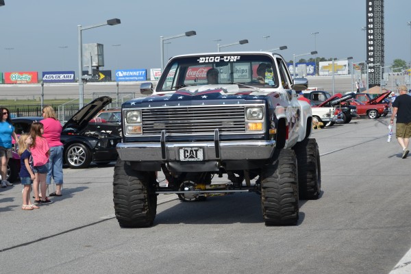 lifted chevy truck with monster truck wheels at large car show