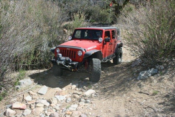a jeep wrangler jk crossing a rocky desert trail