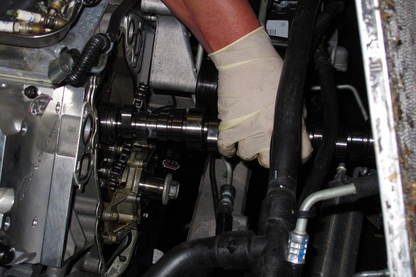 man removing camshaft from a gm ls engine in a c6 corvette