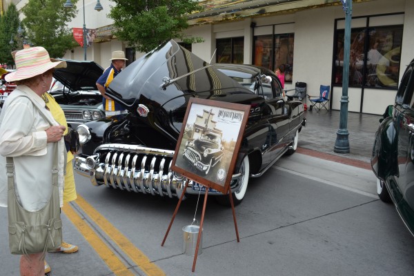 woman reading sign for hot august nights near a classic car