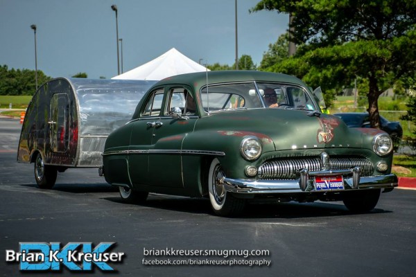 an old mercury postwar coupe pulling a camper trailer
