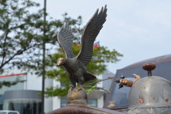 an eagle sculpture welded to the front of a vintage rat rod