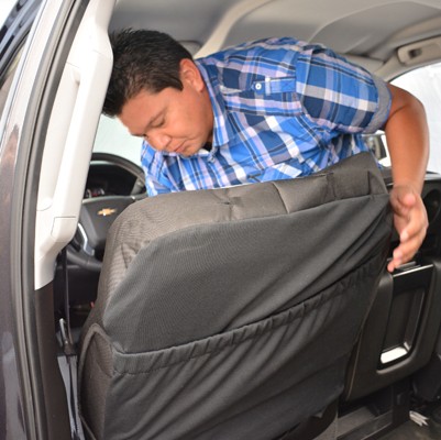 man installing a seat cover onto a vehicle seat