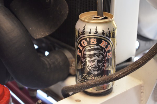 beer can being used as a coolant overflow catch can on a hot rod