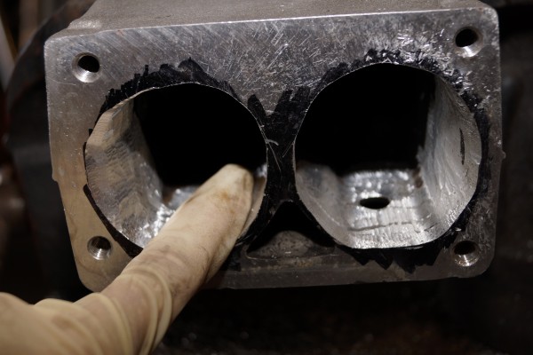 man testing smoothness of an intake port using his finger