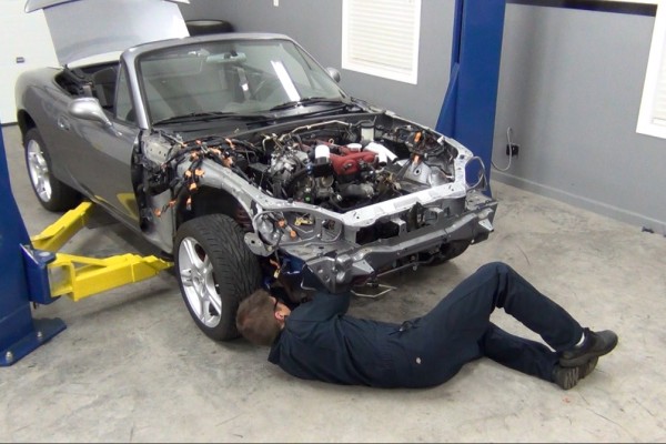 man working on a mazda miata in a shop
