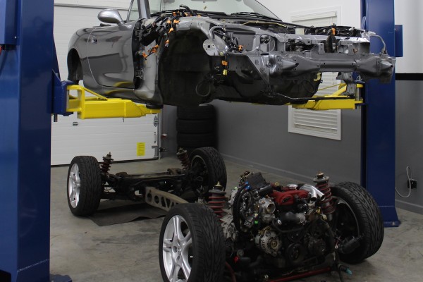 mazda miata body being separated from chassis and engine with a lift
