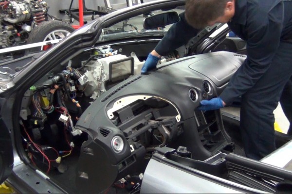 man removing dashboard of a mazda miata