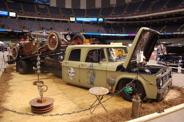 custom four door rat truck with rat rod on its flatbed at a car show