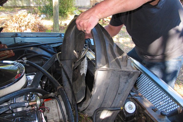 man removing fan and shroud from an old car