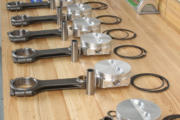 pistons, connecting rods, and rings laid out on a table