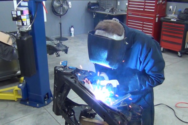 man welding mounting tabs on a mazda miata rear subframe