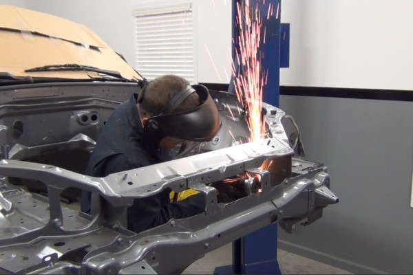 man grinding down radiator support in a mazda miata