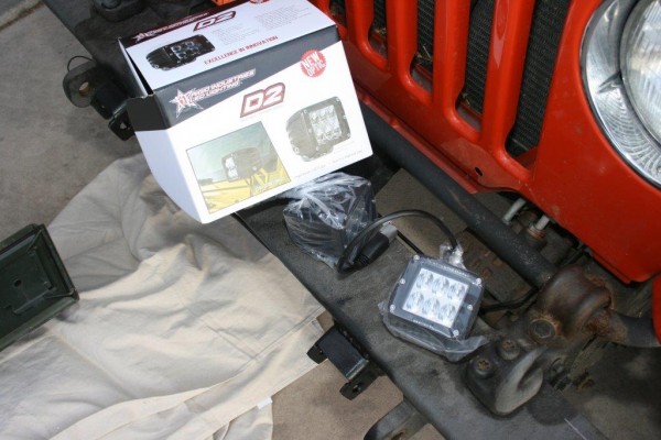 led light pods resting on a jeep bumper prior to install