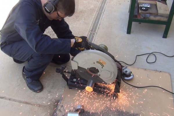 man cutting exhaust tubing with a cutoff saw
