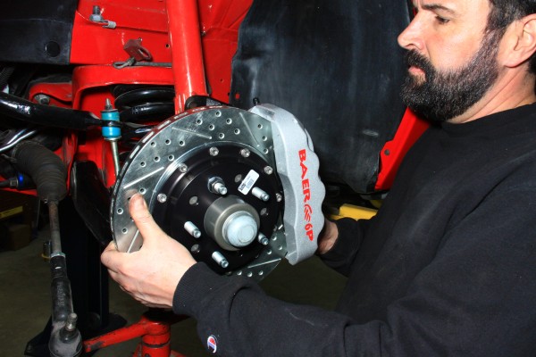 man fitting brake caliper and rotor onto a car